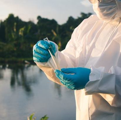 Technicien prélevant un échantillon près d'un cours d'eau, état des risques